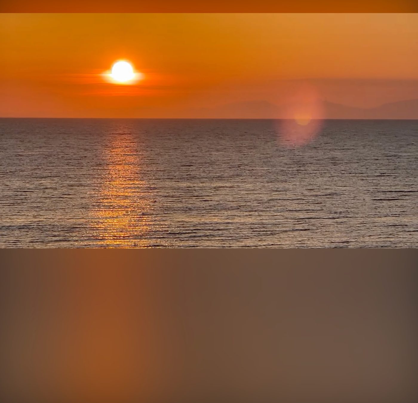 アフターグロウをオンにしたYouTube。夕焼けの映像のオレンジ色が、暗くした画面全体ににじんでいる